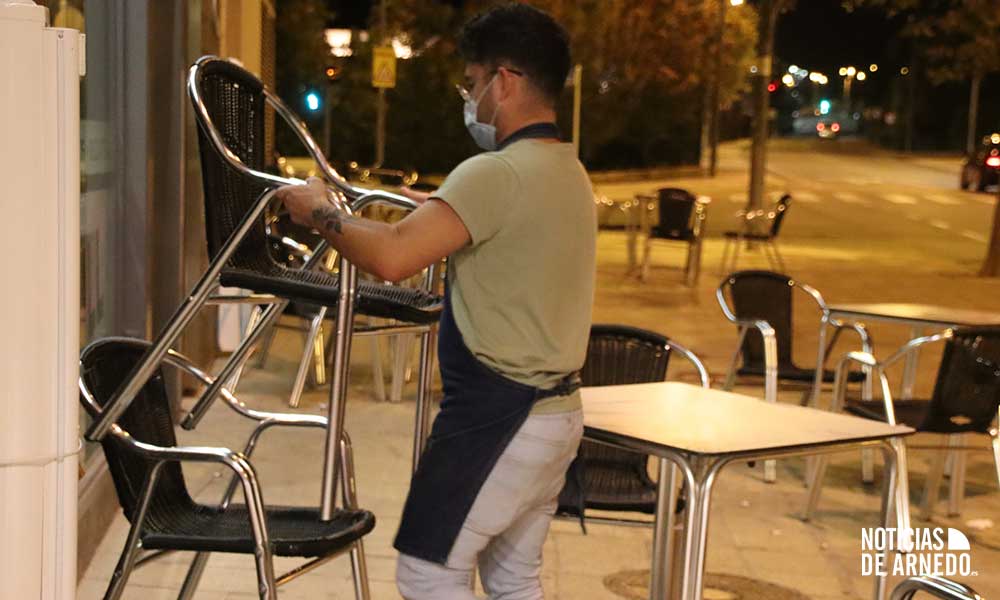 Un camarero desmontando una terraza por la noche en Arnedo